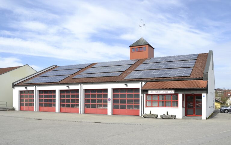 Feuerwehrhaus mit roten Toren und Solarmodulen in Arnstorf, Bayern, fotografiert 2012. Beispielaufnahme, nicht die geplante Feuerwache Gießen-Mitte.